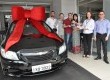 Na foto, o ganhador e sua família recebendo a chave simbólica do novo carro das mãos da equipe Uvel e General Motors